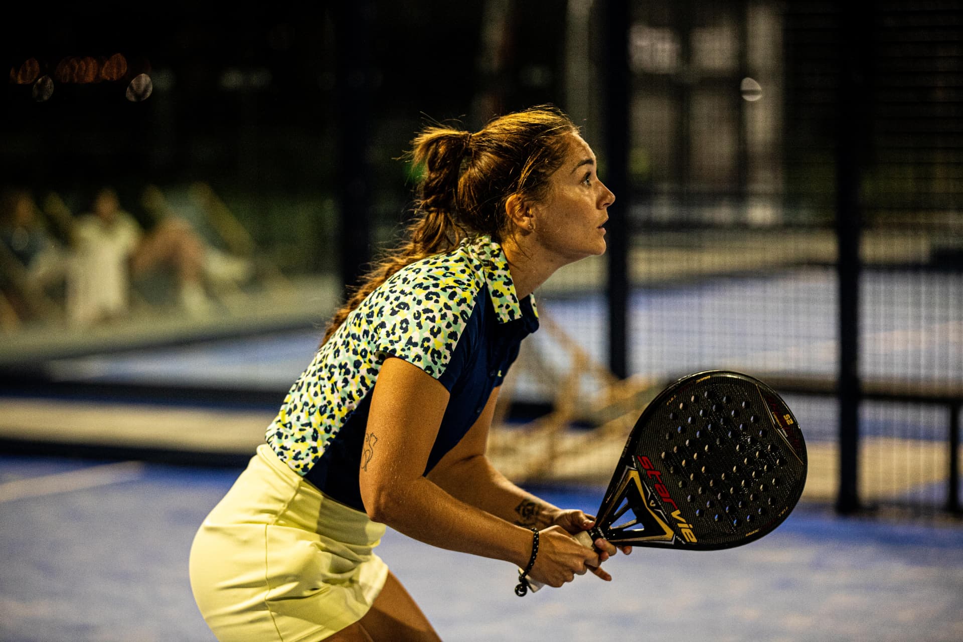 Hráčka padelu v akci pod umělým osvětlením